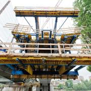 Massima sicurezza sul lavoro con il carro per conci a sbalzo certificato CE. Il team del cantiere in ogni fase di lavoro è protetto a tutti i livelli dalle passerelle di lavoro chiuse. (Foto: Doka)