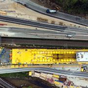 Sowohl Bahnlinie als auch Autobahn laufen parallel zum Bau der Überführungen weiter. Das UniKit-System gewährleistet die vorgeschriebene lichte Höhe für die Durchfahrten und fungiert sowohl als Traggerüst als auch als Schutztunnel für die darunterliegenden Trassees. Copyright: Doka