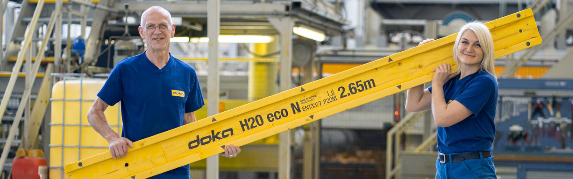 Two factory workers holding beam