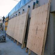 Mobile Konstruktionen aus unbeschichteten Sperrholzplatten schützen die fertiggestellten Sichtbetonwände.